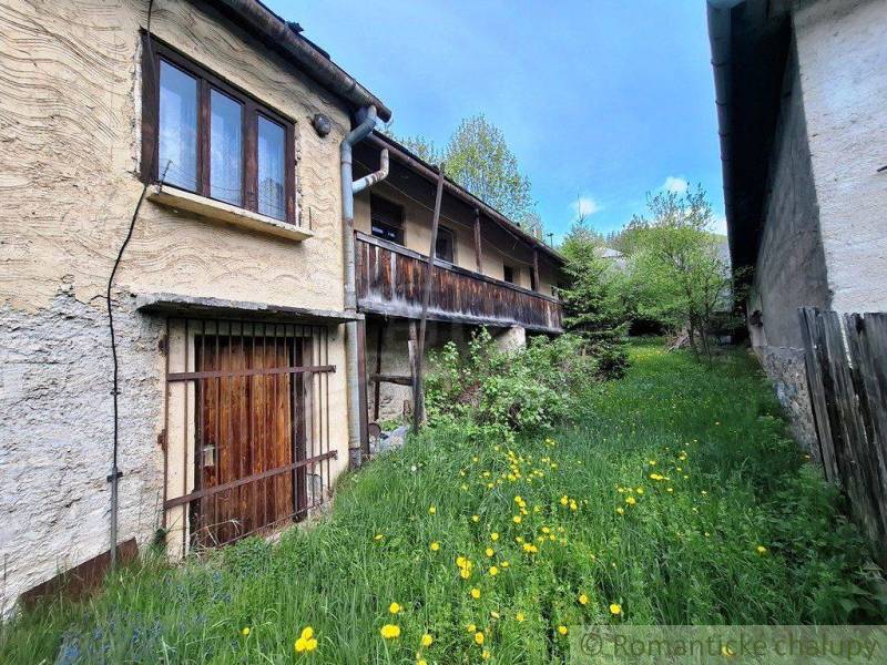 Ein Einfamilienhaus in Pohorelá mit einer Holzveranda, umgeben von Grün und wilden Blumen.