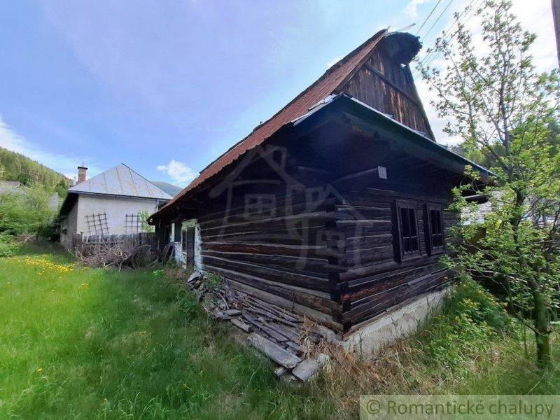 Ein Einfamilienhaus in Pohorelá mit einem alten Holzhaus und einem grasbewachsenen Garten.