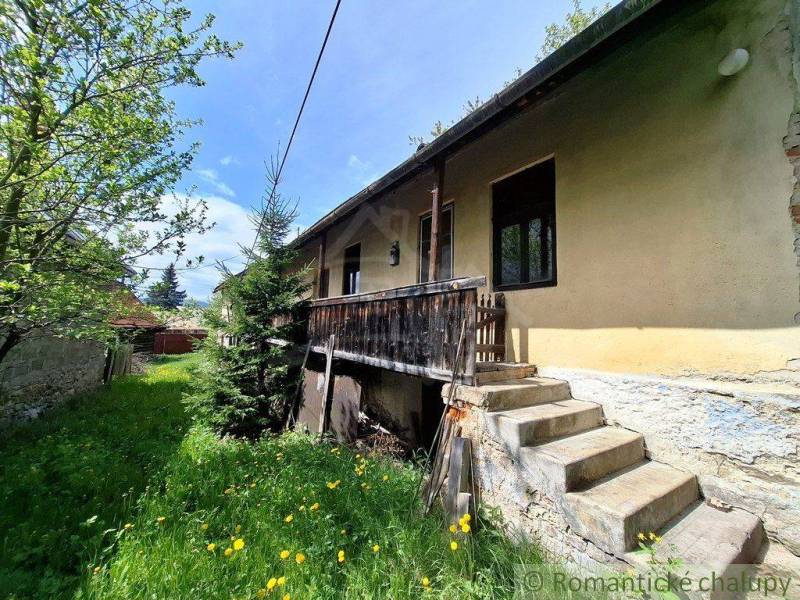 Ein Einfamilienhaus in Pohorelá mit einer Holzterrasse, Treppen und einem Rasen mit Blumen.