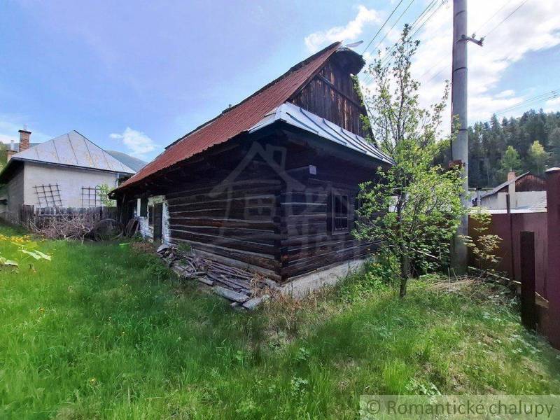 Ein Holzfamilienhaus in Pohorelá, umgeben von Grün, mit einem Blechdach.