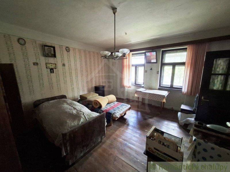 Ein Zimmer in einem Einfamilienhaus mit einem Bett, Holzboden und gemusterten Tapeten.