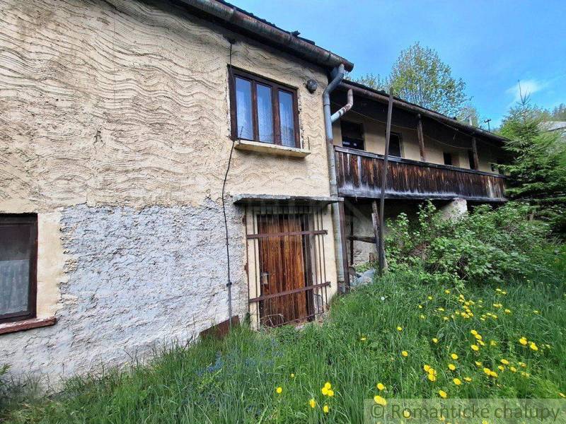 Ein Familienhaus in Pohorelá, mit Steinwänden, einem Holzbalkon, umgeben von Grün und Blumen.