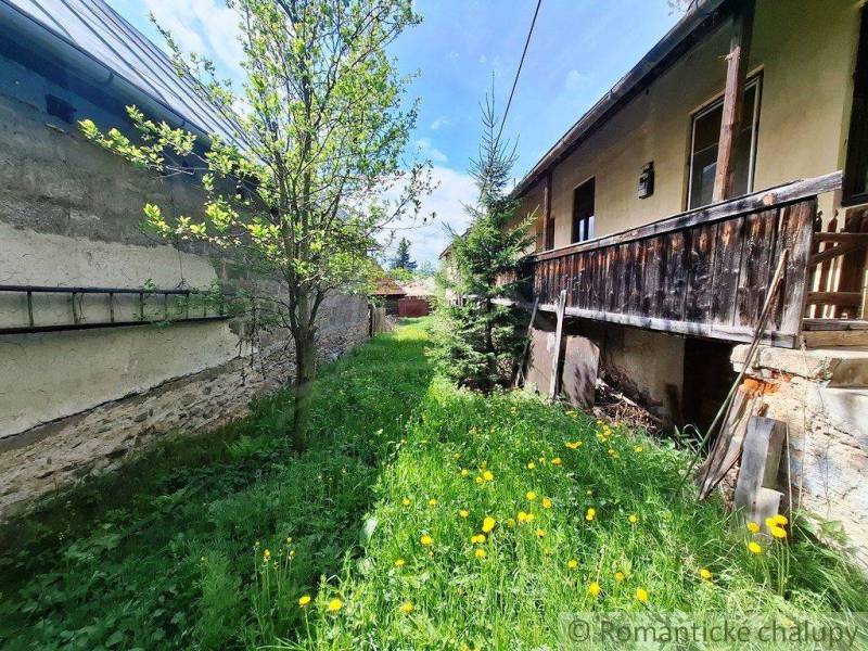 Ein Einfamilienhaus in Pohorelá, ein grasbewachsener Hof mit Blumen und Bäumen, eine Holzveranda.