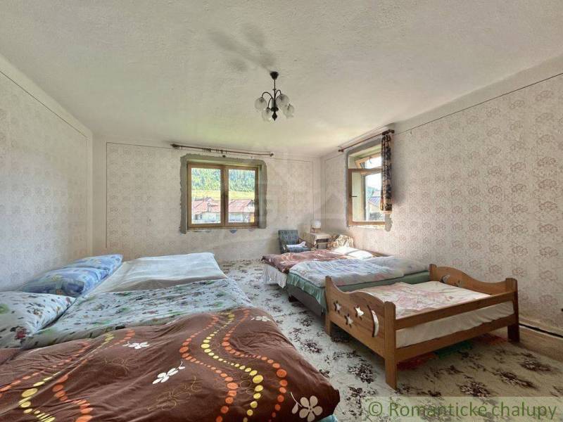 Schlafzimmer in einem Einfamilienhaus mit mehreren Betten, Tapeten und Fenstern mit Aussicht.