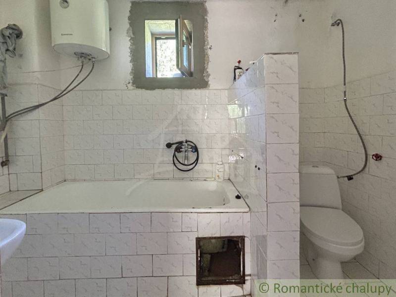 Badezimmer in einem Einfamilienhaus mit Badewanne, Toilette und Gas-Wassererhitzer.