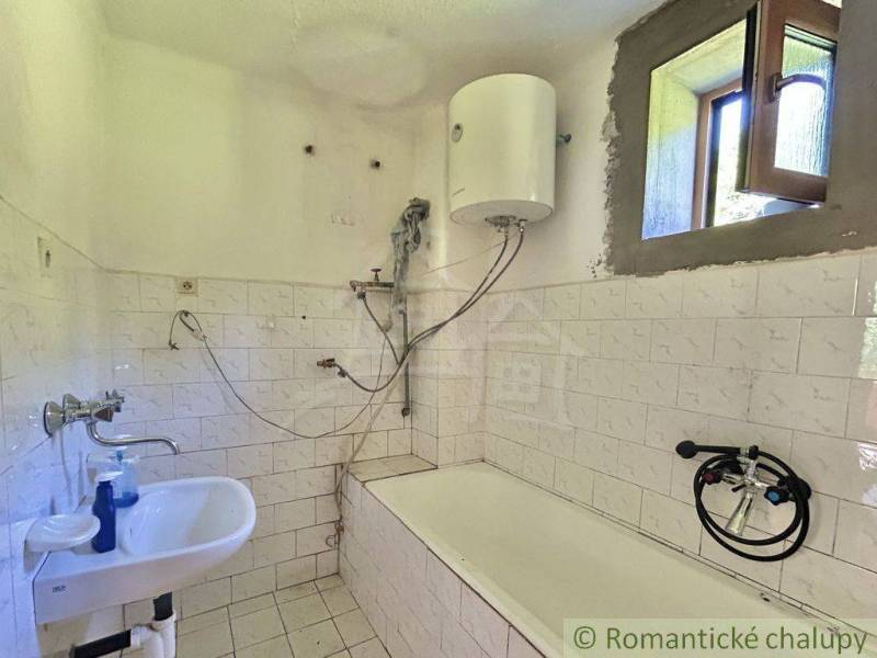 Ein einfaches Badezimmer in einem Einfamilienhaus mit einer Badewanne und einem Boiler an der Wand.