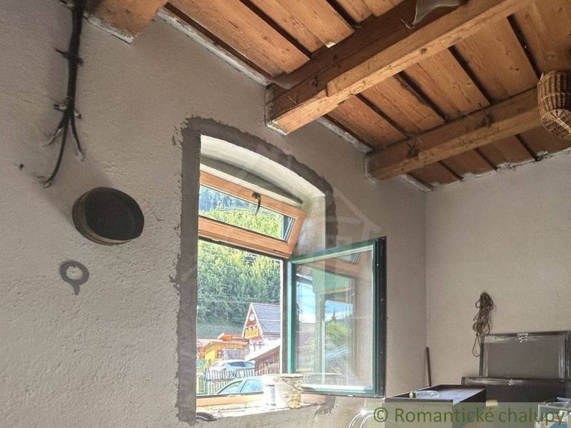 Holzdecke und offenes Fenster mit Aussicht im Innenraum eines Einfamilienhauses.