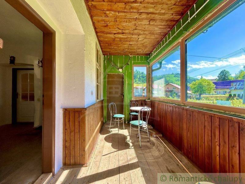 Veranda mit Glas in einem Einfamilienhaus mit Holzstühlen und Blick auf den Garten.