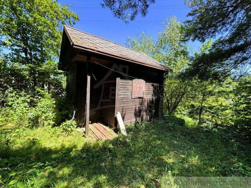 Eine Holzhütte umgeben von Grün in den Gärten von Malacky, der ideale Ort zum Entspannen.