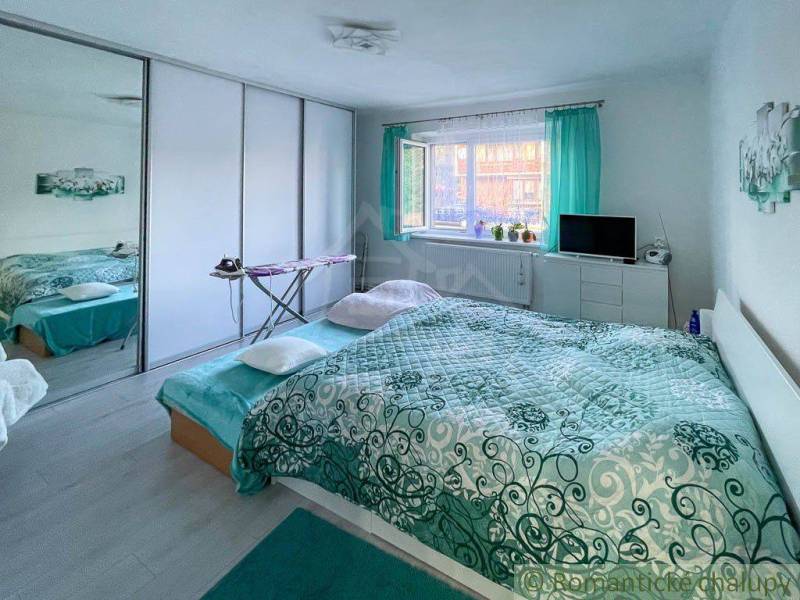 Schlafzimmer im Einfamilienhaus mit großem Bett und grünen Vorhängen, heller Innenraum.