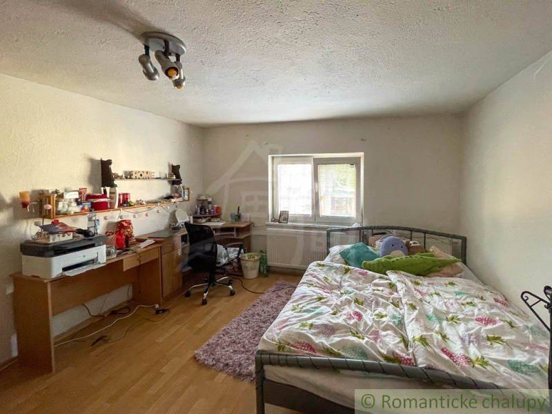 Ein Schlafzimmer in einem Einfamilienhaus mit Bett, Schreibtisch und einfacher Beleuchtung.