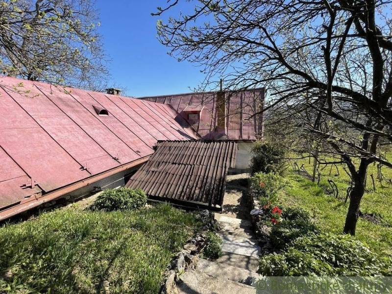 Ein Haus in Rožňava mit einem roten Dach, umgeben von Bäumen und Grün.