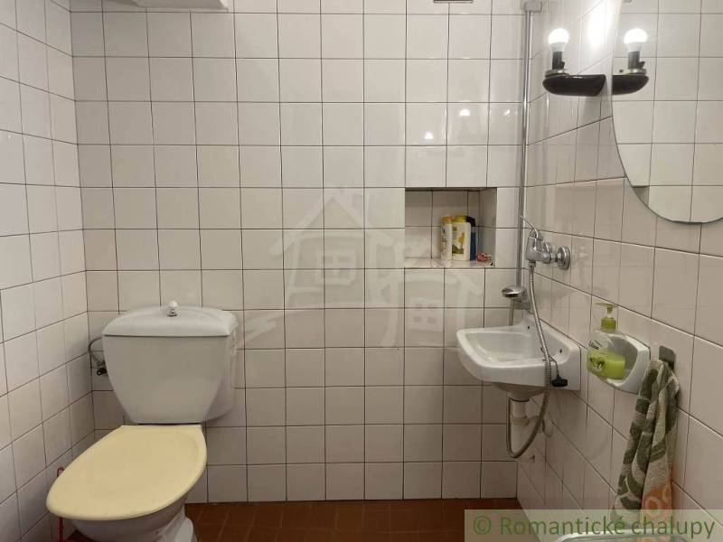 Badezimmer mit Toilette, Waschbecken, Lichtern und weißen Fliesen, besondere Immobilie.
