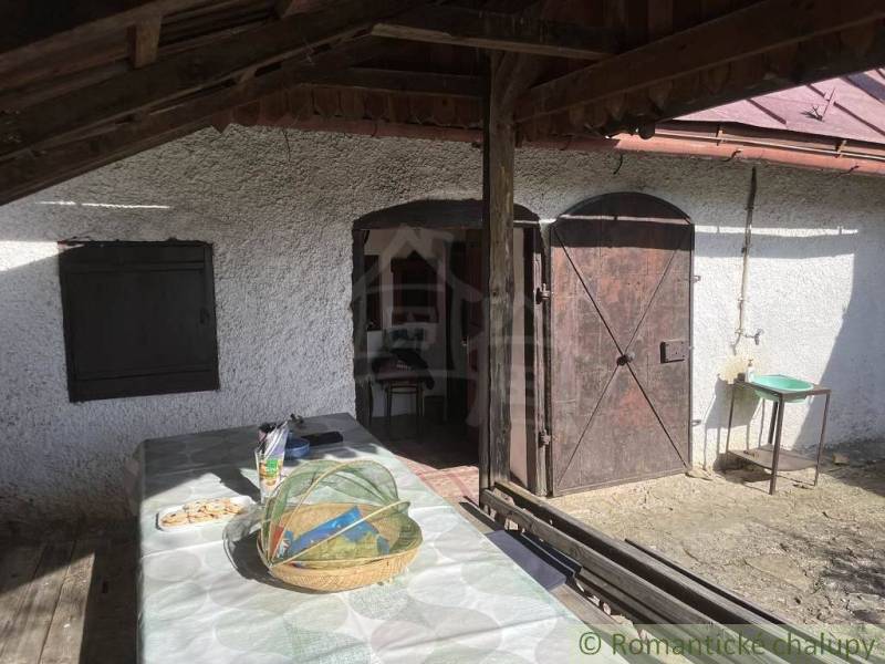 Veranda mit Holztüren bei der Hütte in Rožňava mit einem Tisch und einem Korb.