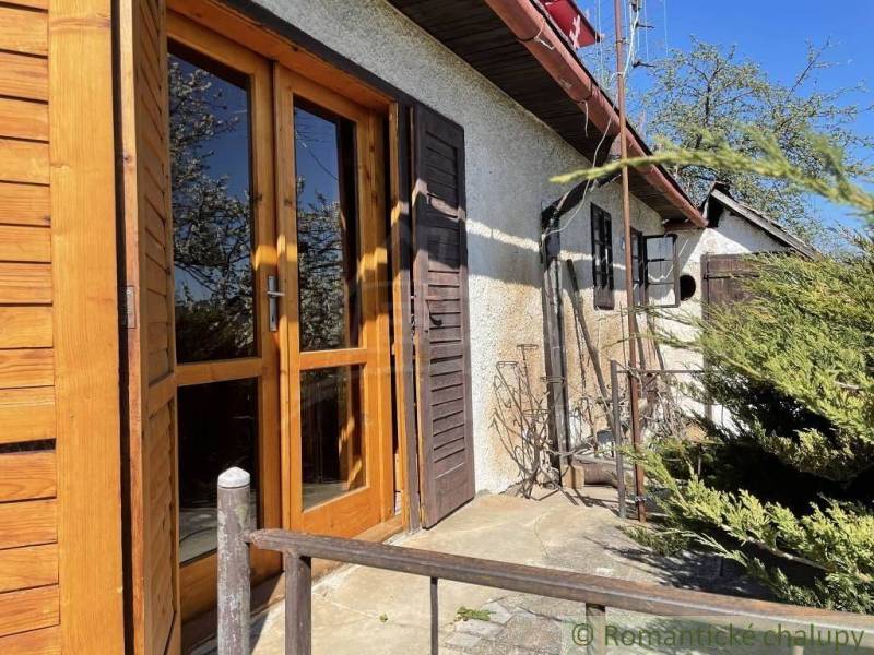 Außenbereich der Hütte mit alten Holztüren und Grün, ideal für besondere Immobilien.