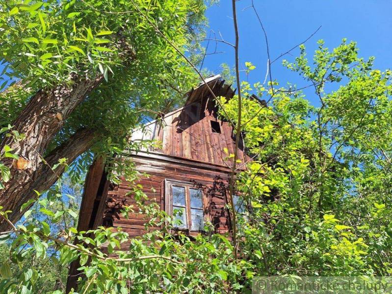 Eine Hütte in Liptovský Mikuláš, umgeben von dichtem Grün unter klarem blauem Himmel.