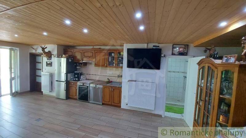 Eine Küche in einem Einfamilienhaus mit Holzdecke, Küchenzeile und einem Fernseher an der Wand.