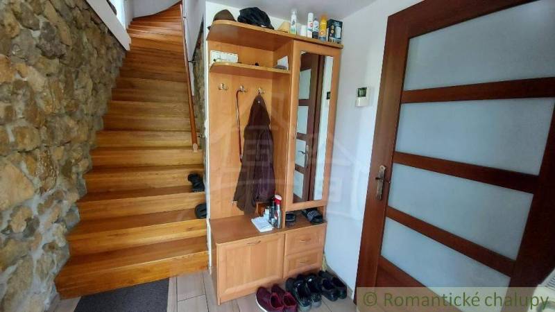 Innenraum eines Einfamilienhauses mit Holztreppe, Schrank und Steinwand.