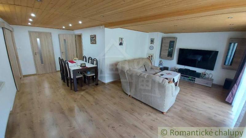 Wohnzimmer und Esszimmer in einem Einfamilienhaus mit Holzbalkendecke und Laminatboden.