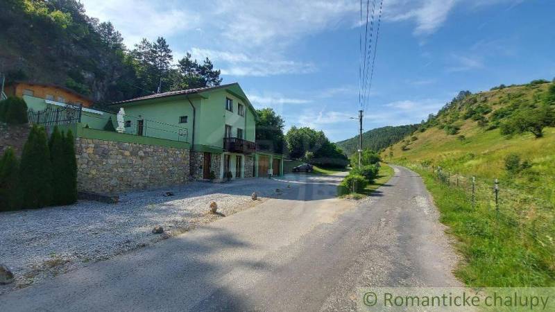 Ein Einfamilienhaus in Dobrá Voda an der Straße, umgeben von grünen Hügeln und Bäumen.