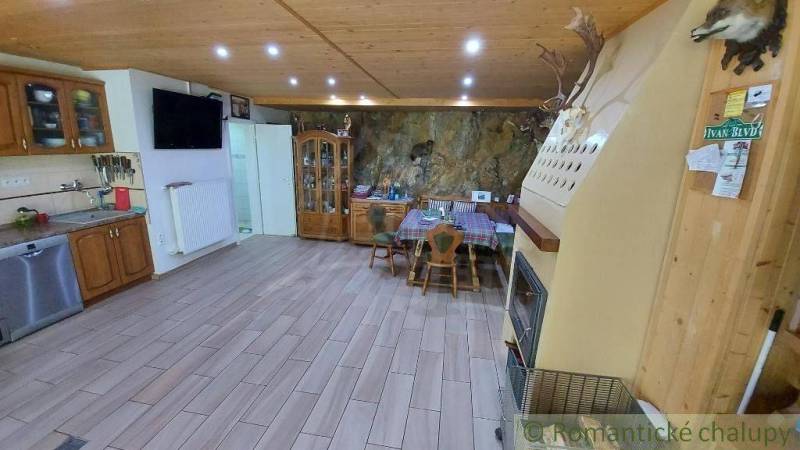Eine geräumige Küche mit Holzbalkendecke, Kamin und Esstisch in einem Einfamilienhaus.