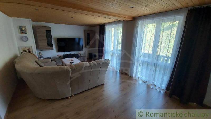 Wohnzimmer in einem Einfamilienhaus mit großem Fernseher und bequemer Couch.