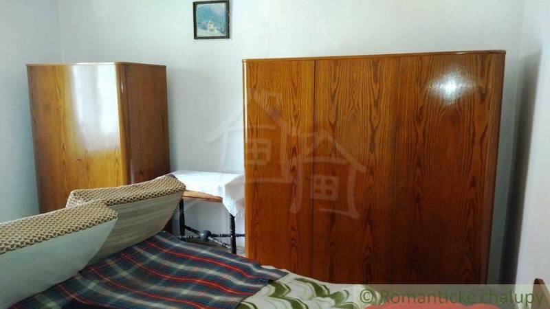 Ein Zimmer in einem Einfamilienhaus mit antiken Schränken und einem Bett mit einer bunten Decke.