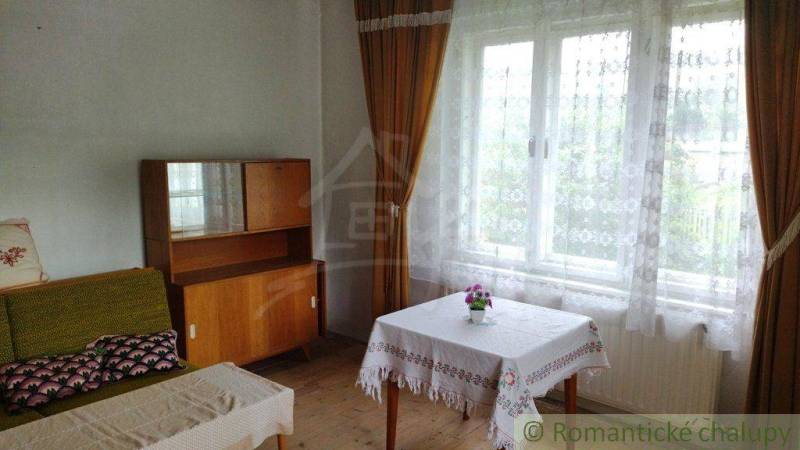 Ein Zimmer in einem Einfamilienhaus mit einer Holzkredenz, einem Sofa und einem Tisch am Fenster.