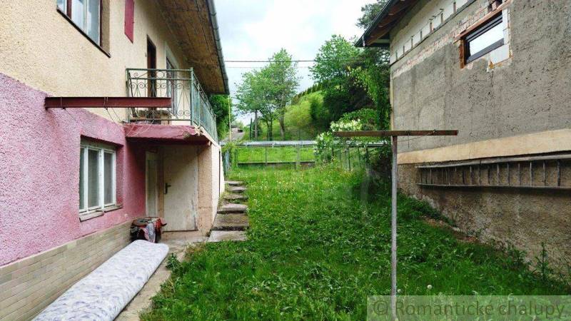 Ein Einfamilienhaus in Fričovce mit einem ungepflegten Garten, neben vernachlässigten Fassaden und einer Treppe.