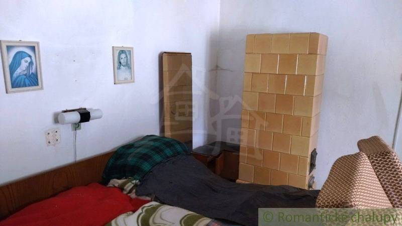 Ein Zimmer in einem Einfamilienhaus mit einem Kachelofen, einem Bett und Wandbildern.