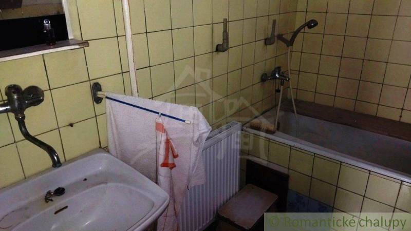 Badezimmer in einem Einfamilienhaus mit Waschbecken, Badewanne und gelben Fliesen.