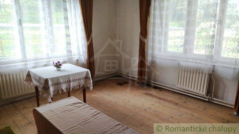 Innenraum eines Einfamilienhauses mit Holzboden, Tisch und langen Vorhängen.