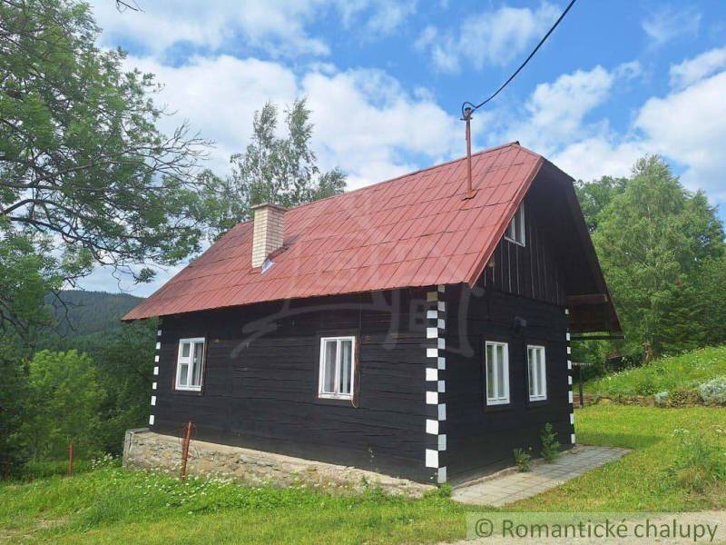 Ein traditionelles Holzhaus in Klokočov mit einem roten Dach, umgeben von Grün und Bäumen.