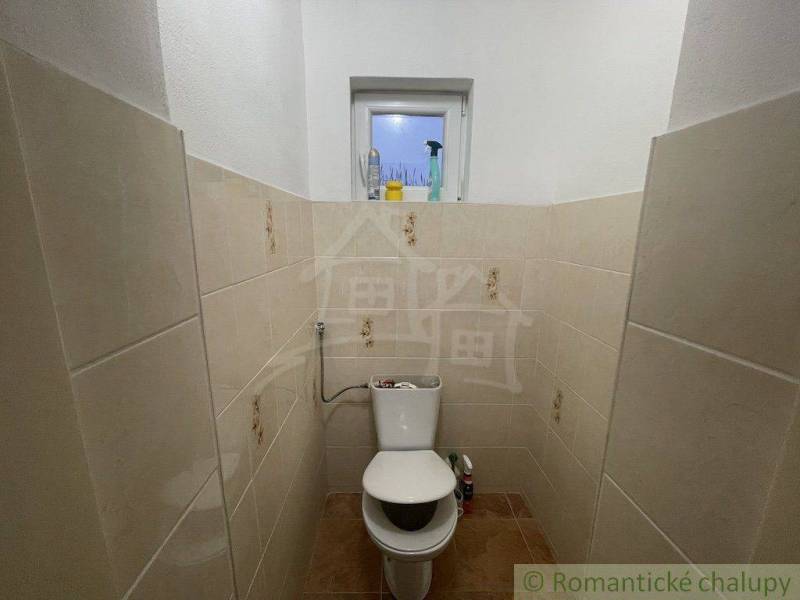 Kleines Badezimmer mit Keramikfliesen, WC und Fenster in einem Einfamilienhaus.