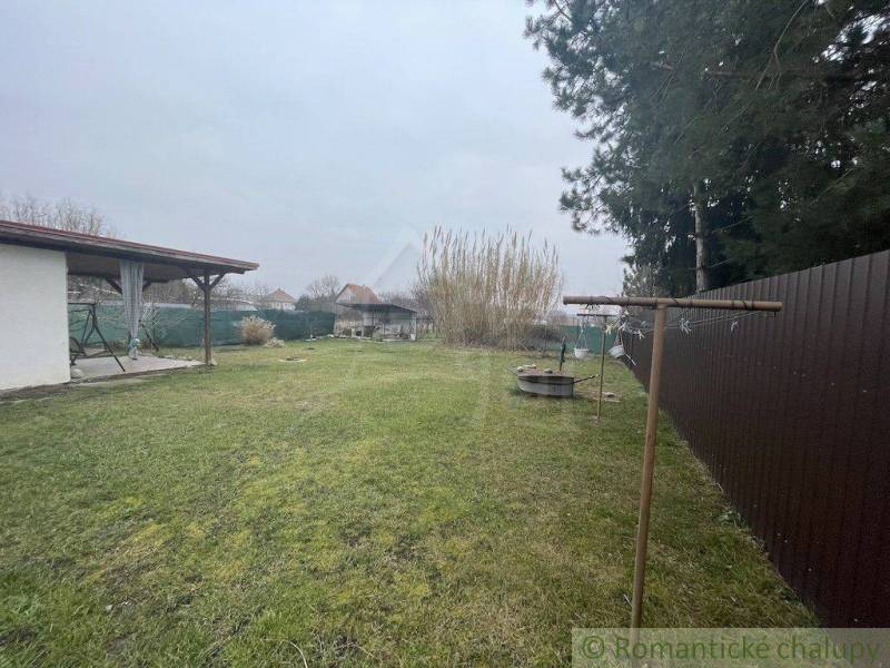 Ein Garten mit Rasen bei einem Einfamilienhaus, ein Pavillon und eine Wäscheleine, ein Holzzaun.