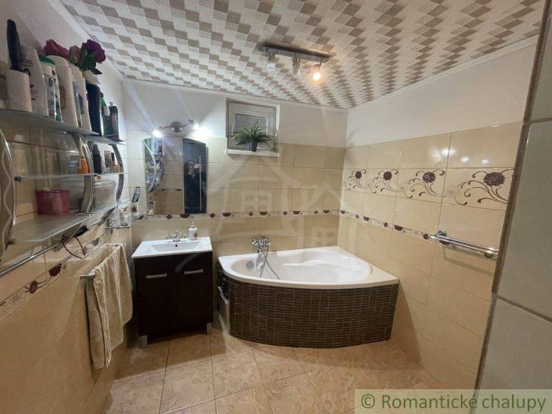 Badezimmer in einem Einfamilienhaus mit Badewanne, Waschbecken, Fliesen und dekorativen Details.