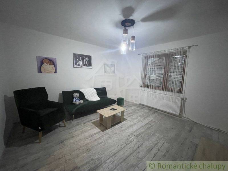 Wohnzimmer in einem Einfamilienhaus mit Sessel, Sofa, Couchtisch und Bildern an den Wänden.