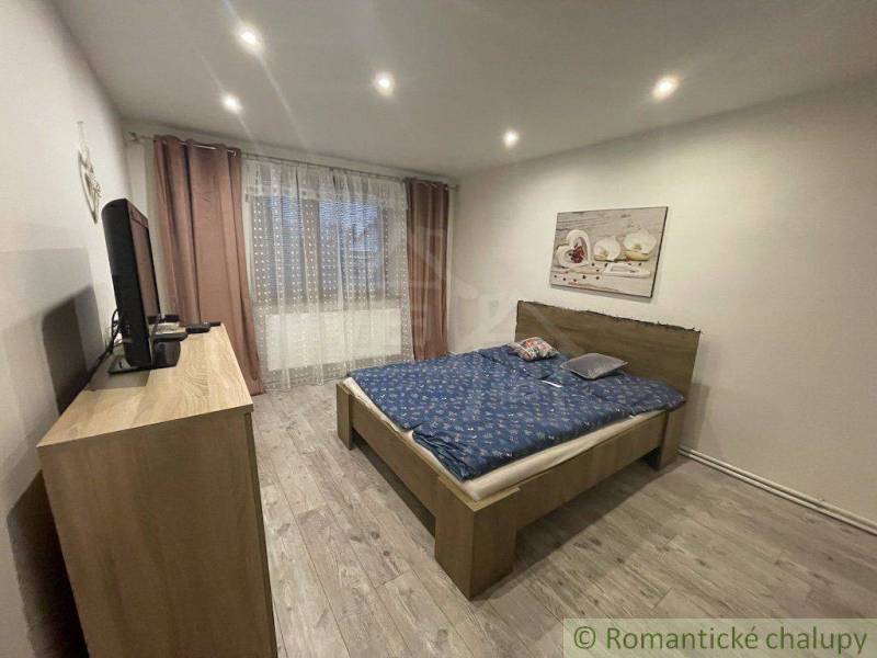 Schlafzimmer mit Doppelbett, Fernseher und Bild, Teil eines Einfamilienhauses.