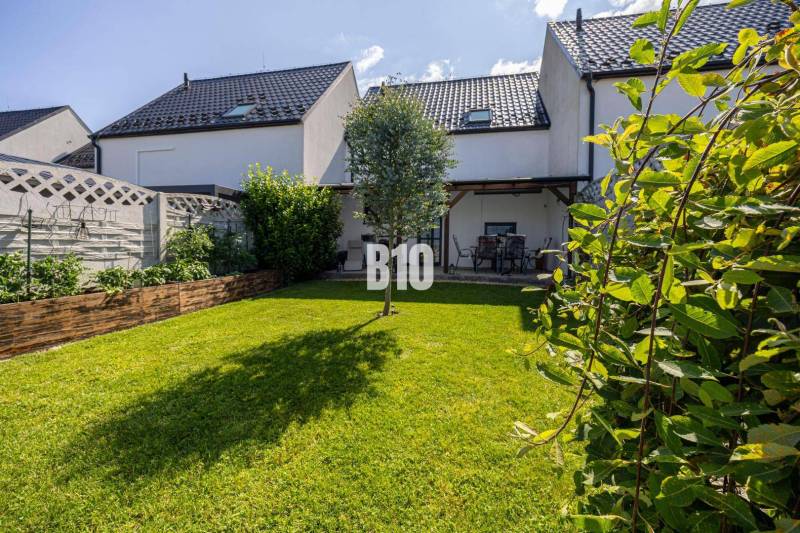 Der Garten des Einfamilienhauses in Stupava mit Rasen, Terrasse und Gartentisch.