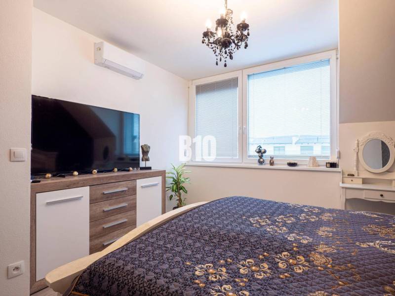 Schlafzimmer in einem Einfamilienhaus mit großem Fernseher und elegantem Kronleuchter.