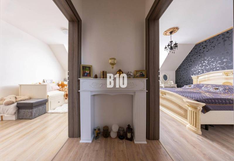 Zwei Zimmer in einem Einfamilienhaus, verbunden durch einen Flur mit dekorativem Kamin.