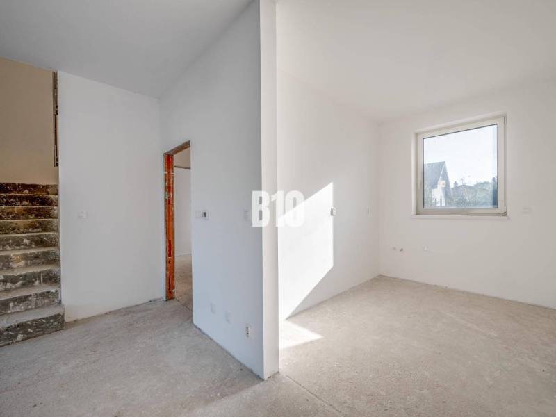 Innenraum eines Einfamilienhauses mit leerem Raum, Treppe und Fenster ohne Bodenbelag.