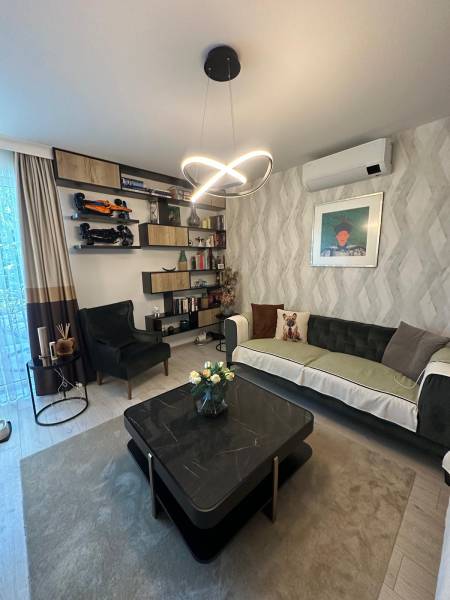 Wohnzimmer in einem Einfamilienhaus, mit einem eleganten Kronleuchter, einem Sofa und Regalen voller Dekorationen.