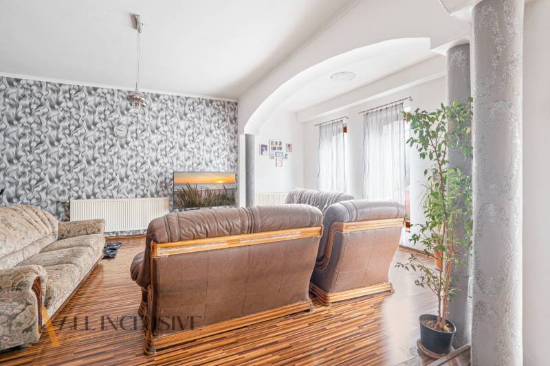 Wohnzimmer mit Ledersofa, gemusterten Tapeten und einer Pflanze im Einfamilienhaus.