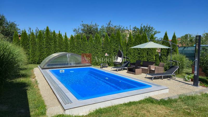 Ein Pool mit Überdachung, Gartenmöbel und Sonnenschirm bei einem Einfamilienhaus in Trenčianske Jastrabie.