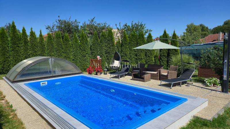 Ein Pool mit Gartenmöbeln und Liegestühlen in einem Einfamilienhaus in Trenčianske Jastrabie.