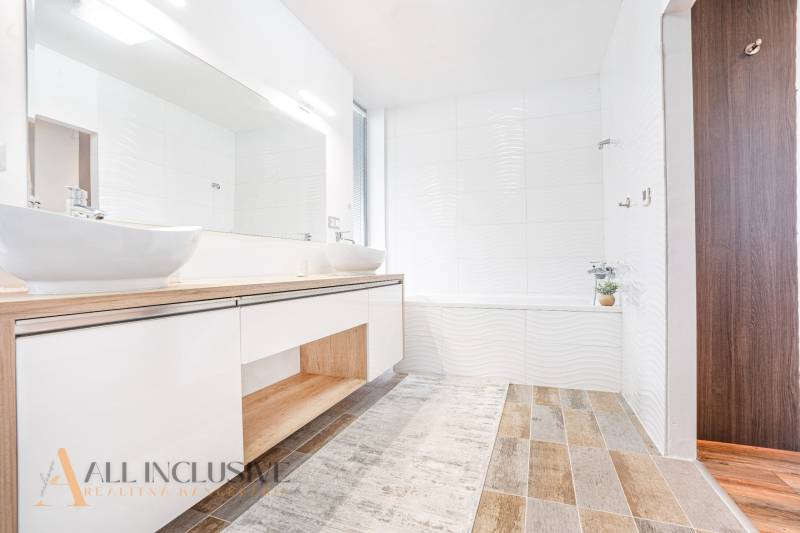 Ein Badezimmer in einem Einfamilienhaus mit Waschbecken, weißen Wänden und Holzboden.