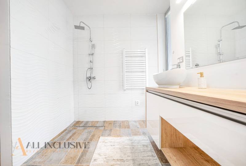 Badezimmer in einem Einfamilienhaus mit Waschbecken, Dusche und weißen Fliesen.