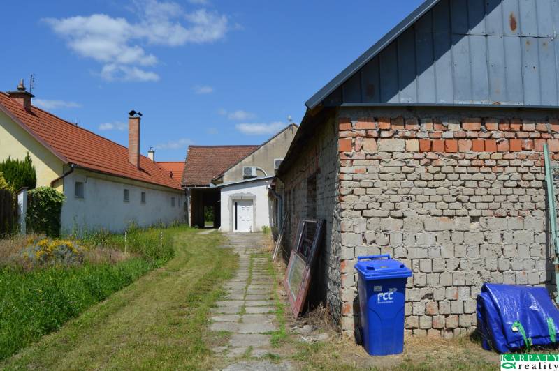 Geschäftsräume in Borský Svätý Jur, Gebäude mit rotem Dach, Rasen und blauer Container.