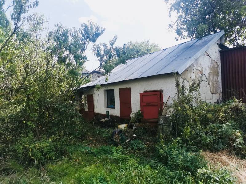 Ein Einfamilienhaus in Sobrance, umgeben von dichtem Grün, mit alter Putzfassade und roten Türen.